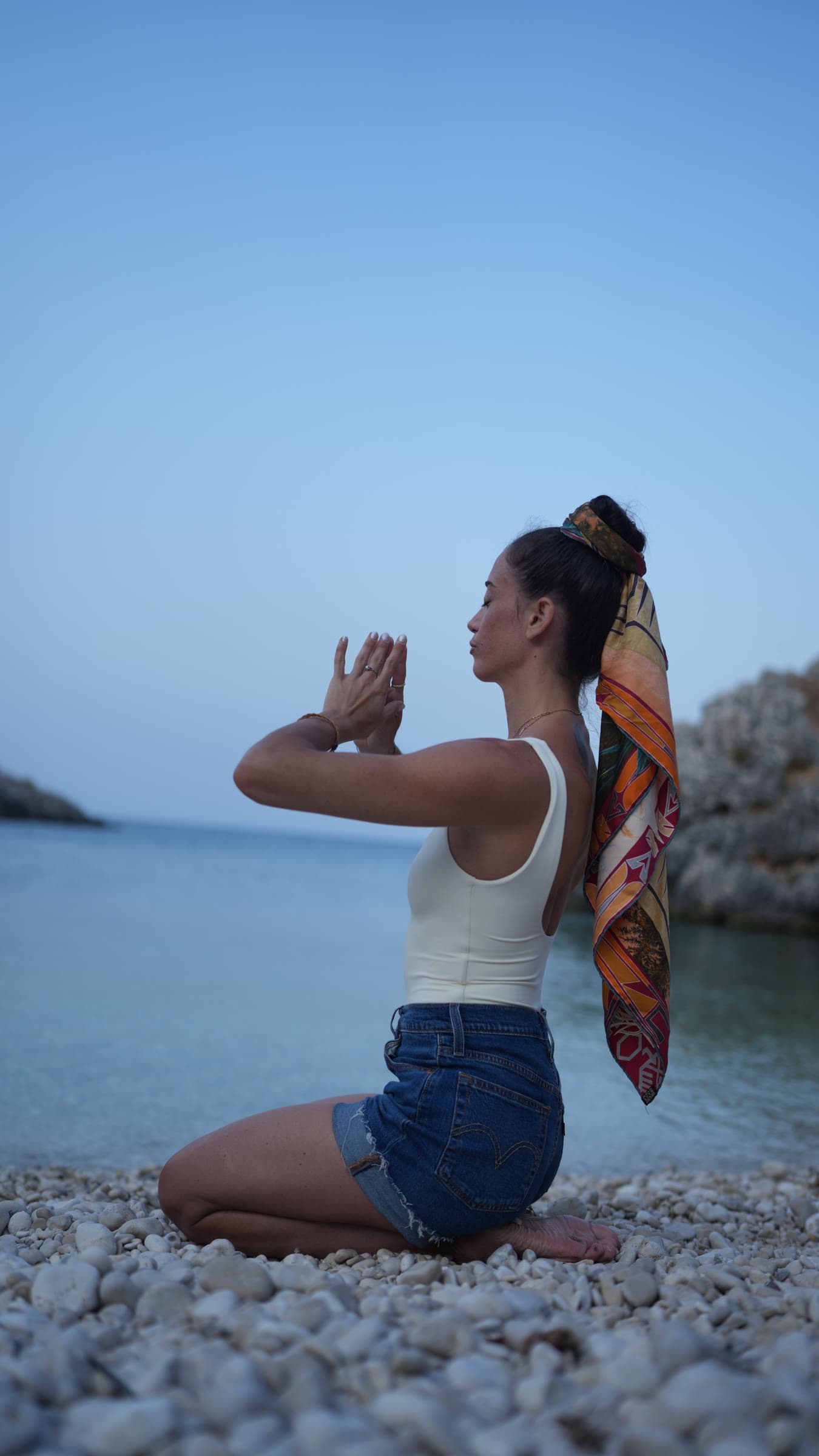 Francesca in ginocchio sulla spiaggia, le mani giunte davanti al viso